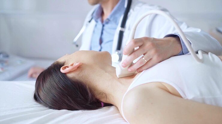 Photo 医師は,医学的検査のために横たわっている女性患者の首に超音波装置を使用しています. 医学と科学