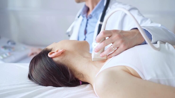 Photo 医師は,医学的検査のために横たわっている女性患者の首に超音波装置を使用しています. 医学と科学