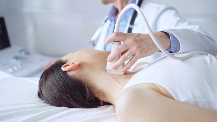 Photo 医師は,医学的検査のために横たわっている女性患者の首に超音波装置を使用しています. 医学と科学