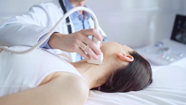 Photo 医師は,医学的検査のために横たわっている女性患者の首に超音波装置を使用しています. 医学と科学