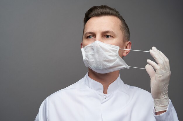 Doctor man wearing protective latex gloves and face mask, close-up