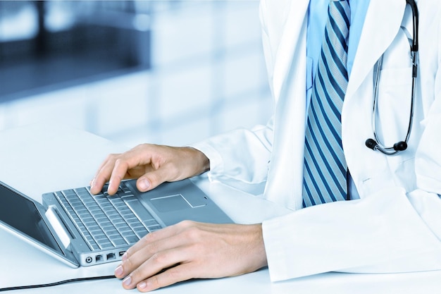 Doctor man in white suit using laptop on background