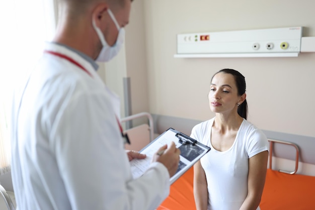 Doctor in mask communicates with patient in clinic ultrasound and medical diagnosis concept