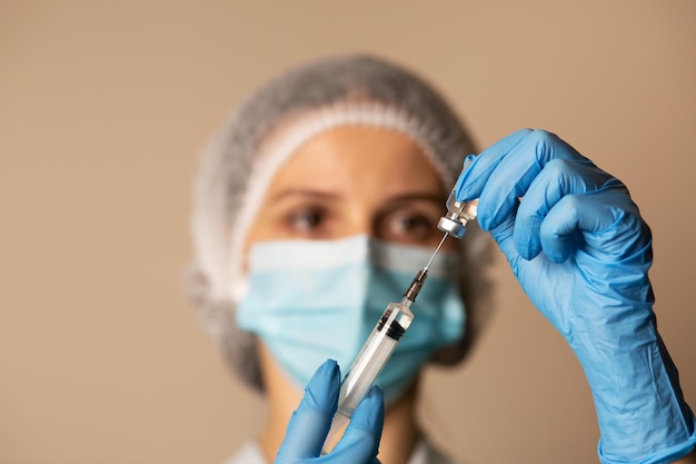 Doctor in a mask filling syringe with a medication