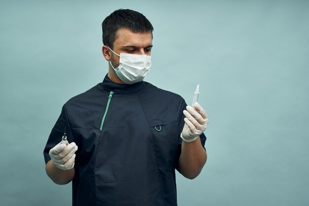 Doctor in a mask holds an ampoule and a syringe in his hands