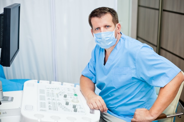 Doctor in mask with ultrasound equipment