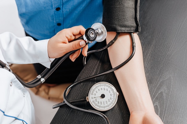 의사는 의료 약속에서 여성 환자에게 안압계로 혈압을 측정합니다.