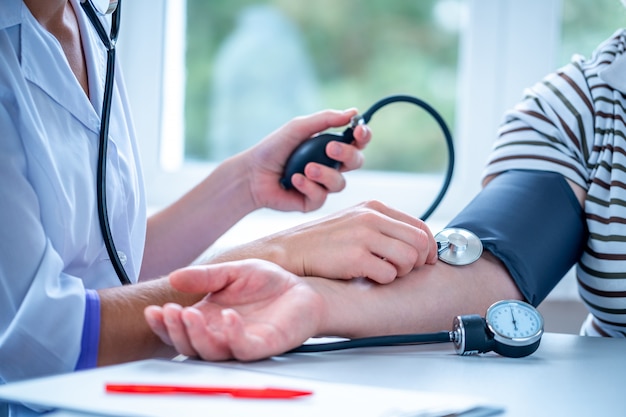 Doctor measures the pressure of the patient during a medical examination and consultation in the hospital.