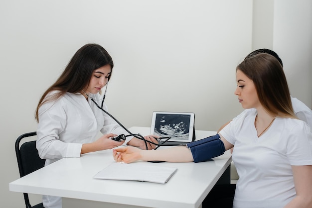 Il medico misura la pressione di una ragazza incinta in clinica. gravidanza e assistenza sanitaria.