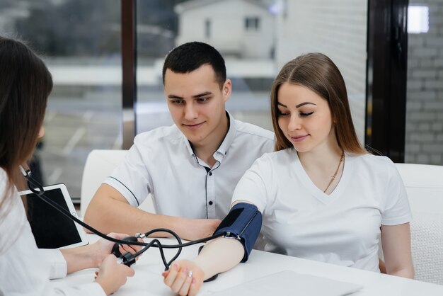 Il medico misura la pressione di una donna incinta nella clinica. gravidanza e assistenza sanitaria