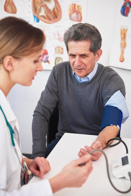 Foto il medico misura la pressione nel paziente anziano