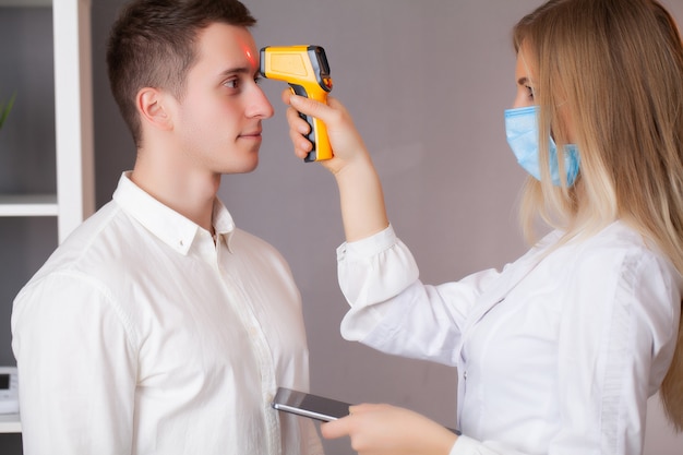 Doctor measures the temperature of a patient during an epidemic covid-19.