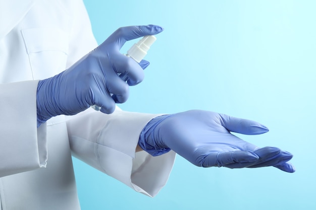 Doctor in medical gloves hold antiseptik on blue isolated background