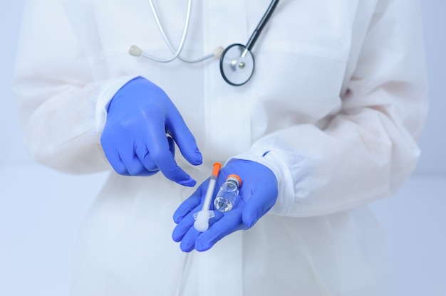 Doctor in medical gloves and a mask holds a vaccine in his hands