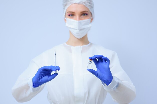 Doctor in medical gloves and a mask holds a vaccine in his hands