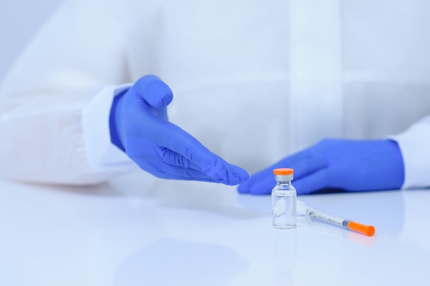 Doctor in medical gloves and a mask holds a vaccine in his hands