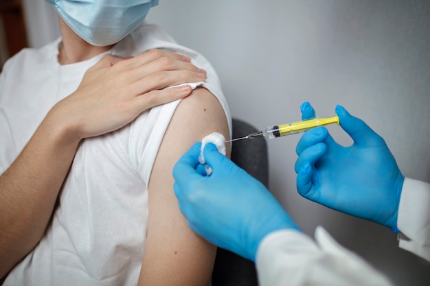 コロナウイルスワクチンでアンプルと注射器を保持している医療マスクと手袋の医師