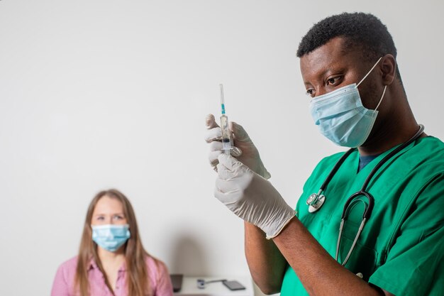 Doctor in medical mask holding syringe with medication