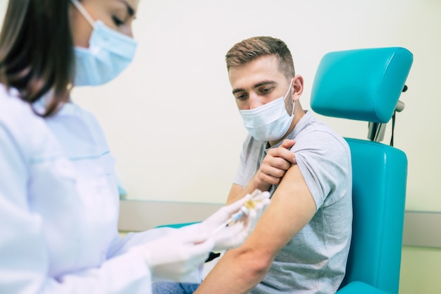 Il dottore con la maschera medica si sta preparando per il concetto di vaccinazione uomo, medicina e farmaco.