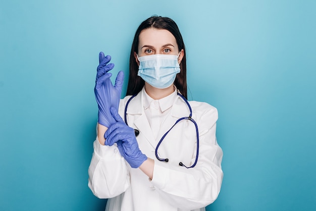 Doctor in medical mask, put on rubber gloves for examination