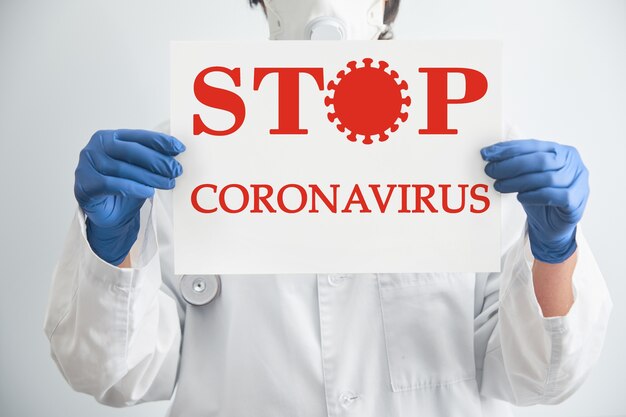 Doctor in a medical mask shows the tablet with the words STOP VIRUS. Coronavirus epidemic protection.