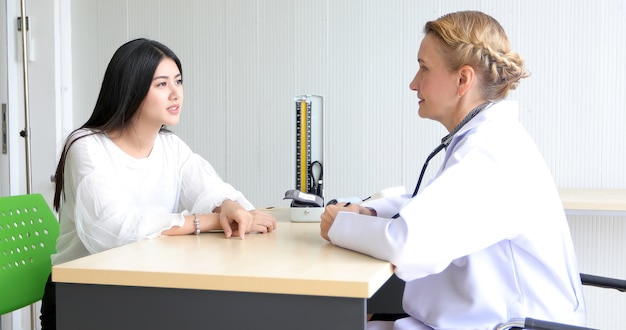 Doctor meeting and explaining medication to woman patient in his office at Hospitals