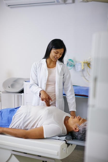 Doctor mri and woman comfort patient in hospital before scanning in machine Ct scan holding hands and happy medical professional with senior female person before radiology test for healthcare
