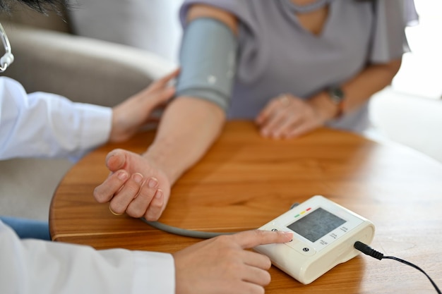 Doctor or nurse checking patient's blood pressure with blood pressure monitor