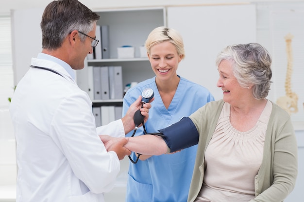 Doctor and nurse checking senior patients blood pressure