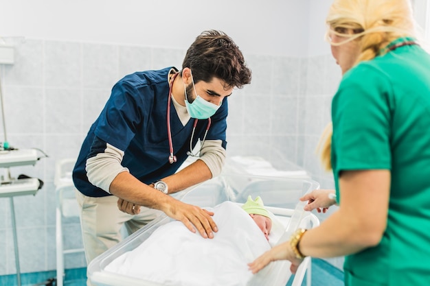 Doctor and nurse examining newborn baby in hospital.