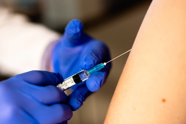 Doctor or nurse giving  or vaccine to a patient's shoulder