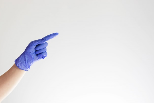 Doctor or nurse hand in blue glove, gesture with forefinger. Index finger pointing to the right.