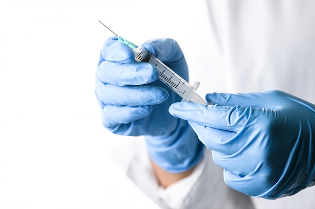 Doctor or nurse hand holding flu vaccine shot, measles injection syringe 