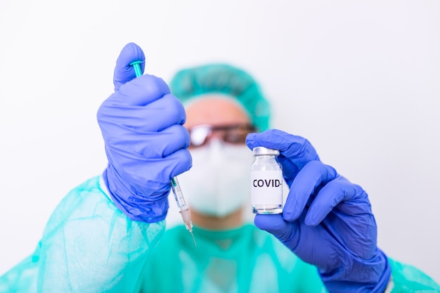 Рука доктора или медсестры при нитриловая перчатка держа грипп Вакцина COVID-19, вакцина против кори снятая для концепции вакцинации младенца, медицины и лекарства. Коронавирус вакцина