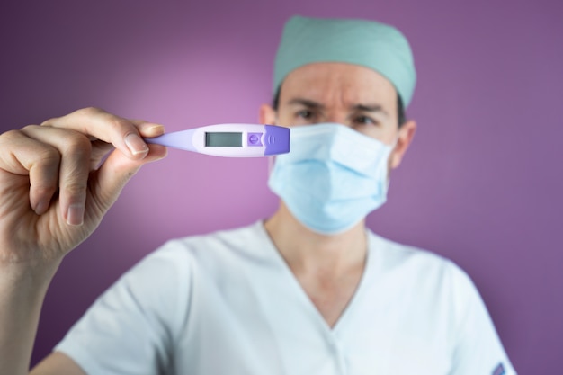 Doctor nurse looking at a patient with temperature with a thermometer because of Coronavirus Covid-19