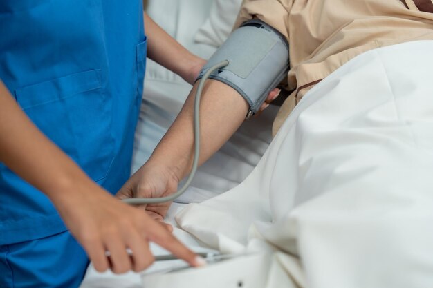 Doctor and nurse measuring blood pressure of patient in recovery room after treatment