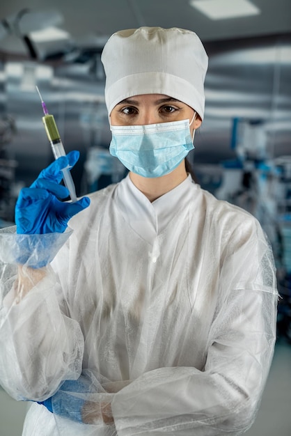 Doctor or nurse in medical mask holding syringe with injection or medicine