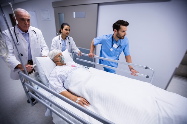 Doctor and nurse pushing emergency stretcher bed in corridor