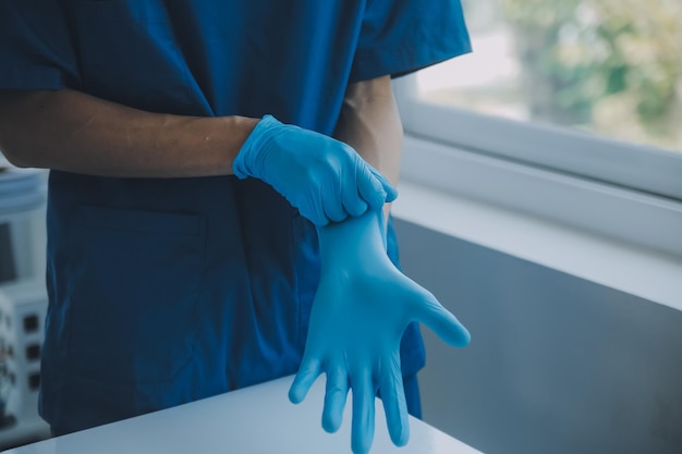 Doctor or nurse putting on blue nitrile surgical gloves professional medical safety and hygiene for surgery and medical exam on white background