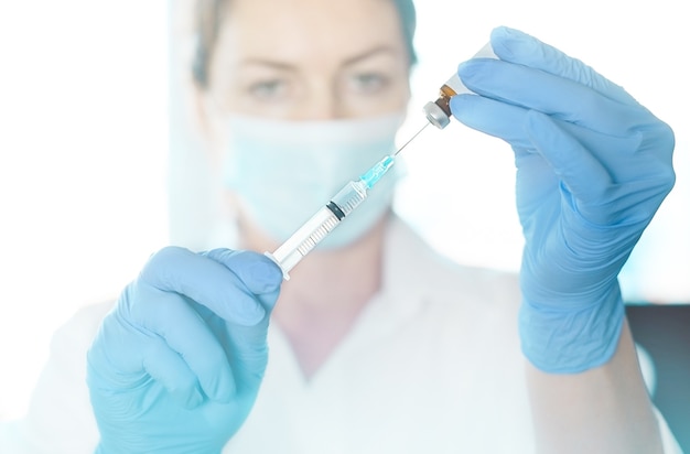 의사, 간호사, 과학자, 연구원이 독감, 홍역, 코로나 바이러스, covid-19 백신을 들고 파란색 장갑을 끼고 있습니다.