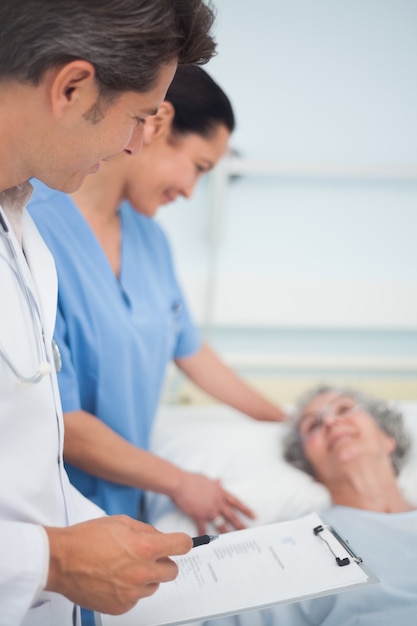 Doctor and nurse standing next to a patient