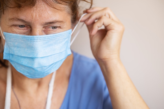 Doctor or nurse taking off her medical mask, portrait, close up, white background, copy space.