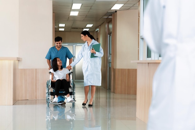 Doctor and nurse transport female patient in wheelchair at sterile corridor