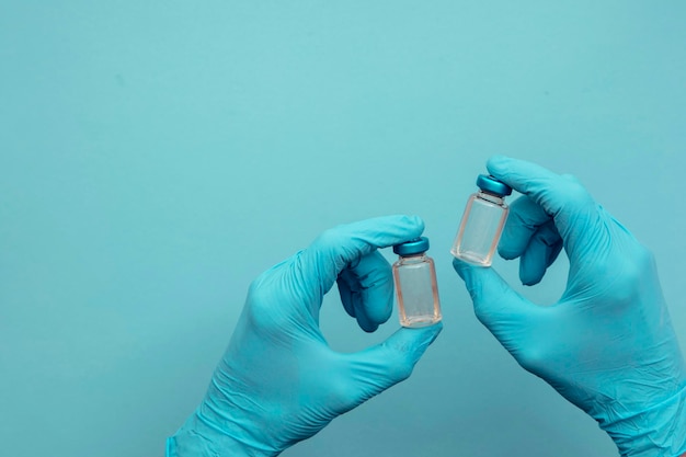 Doctor or nurse wearing blue surgical gloves holding a double vaccine dose