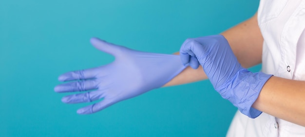 Doctor or nurse in white medical suit puts on protective gloves Closeup Concept of professional