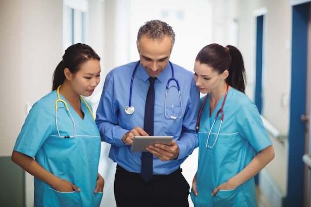 Doctor and nurses discussing over digital tablet