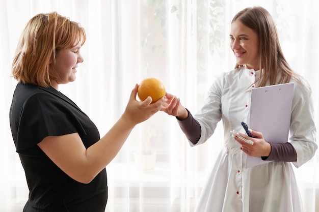 Doctor nutritionist, dietitian and female patient on consultation in the office. young smiling