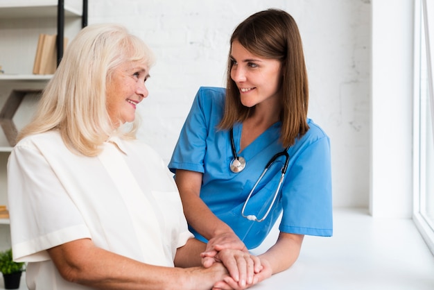 Doctor and old woman holding hands 