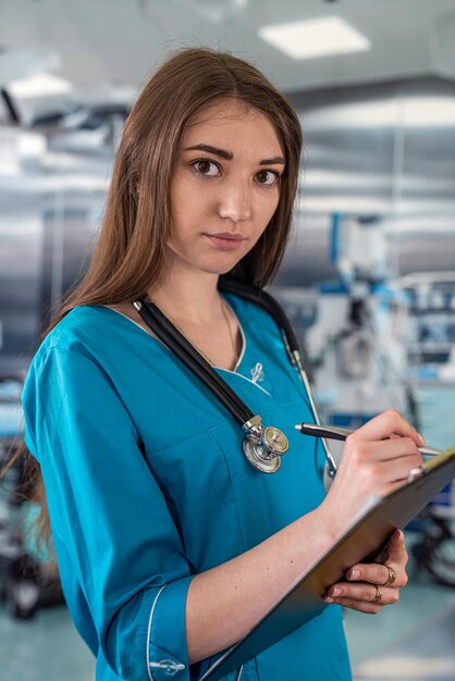 Doctor in operating room in a modern clinic is writing on a clipboard with information