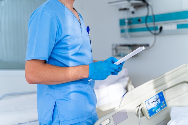 Doctor in operating room with folder in hands. Doctor in hospital chamber. Modern medical background. Selective focus.